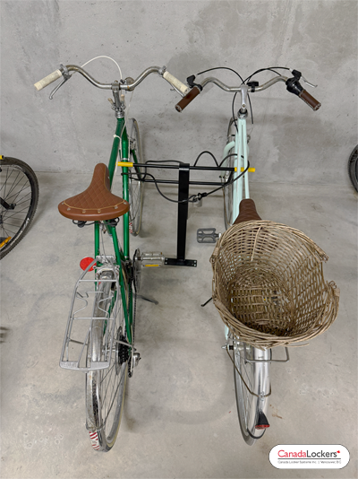 A pleasant photo of a bike rack being used to secure 2 beach cruiser bikes inside a bike room. Bike Parking in action.